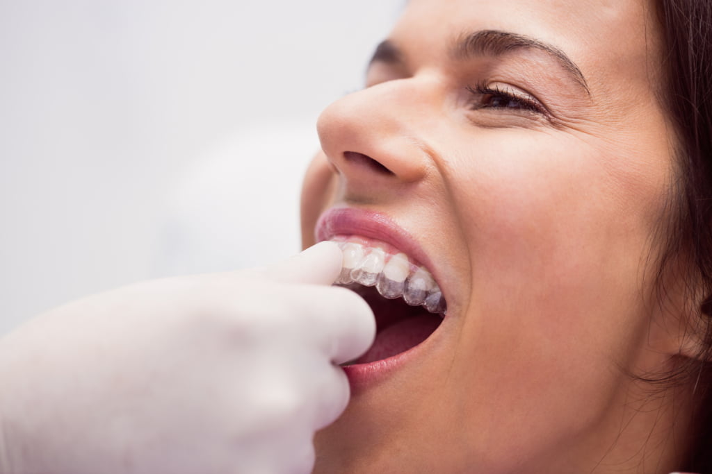 Dentist assisting female patient to wear braces in dental clinic
