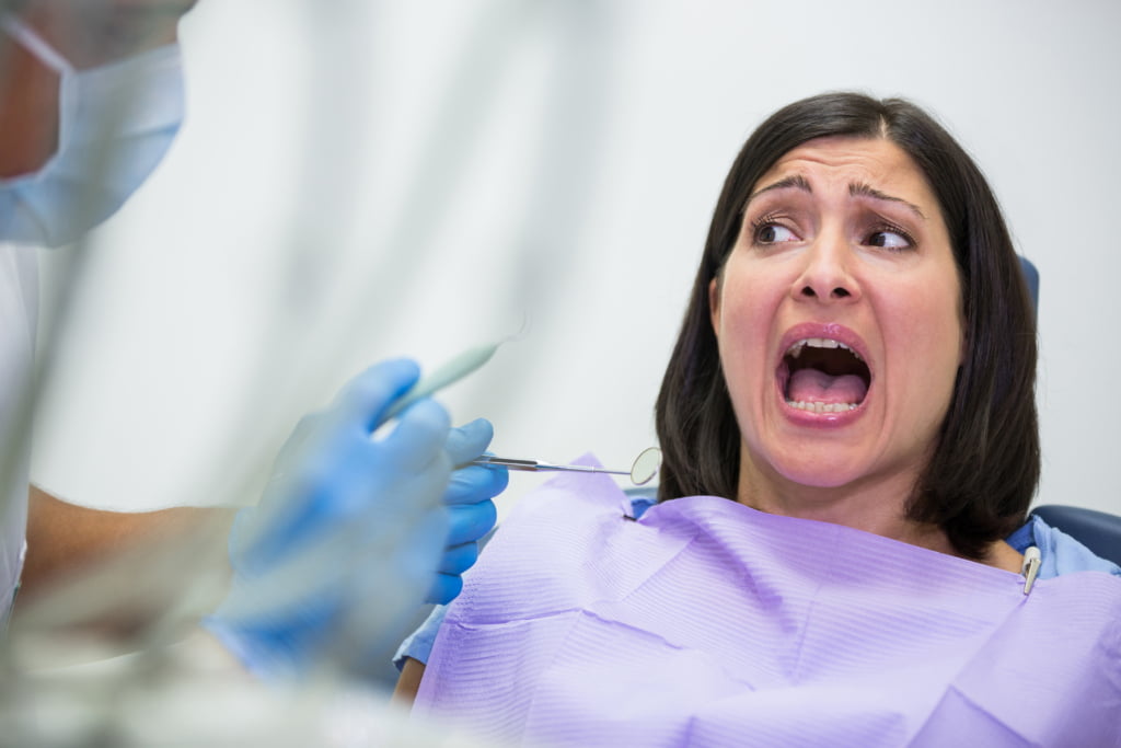 female patient scared looking at dental tool