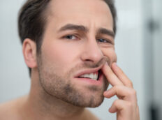 man checking out teeth looking worried
