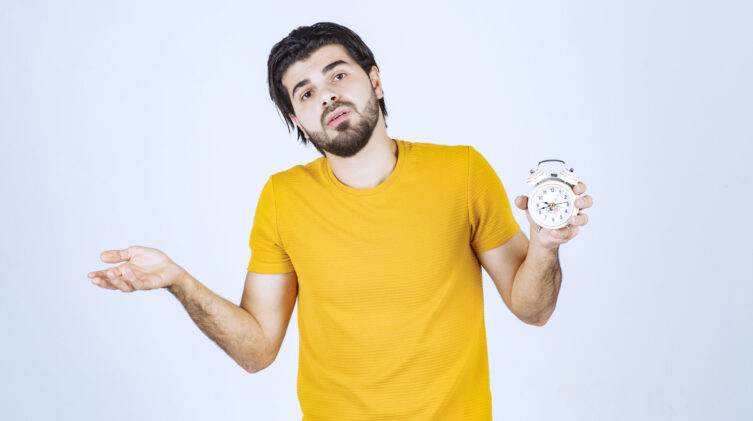 man holding a clock, looking like he is wondering or confused.